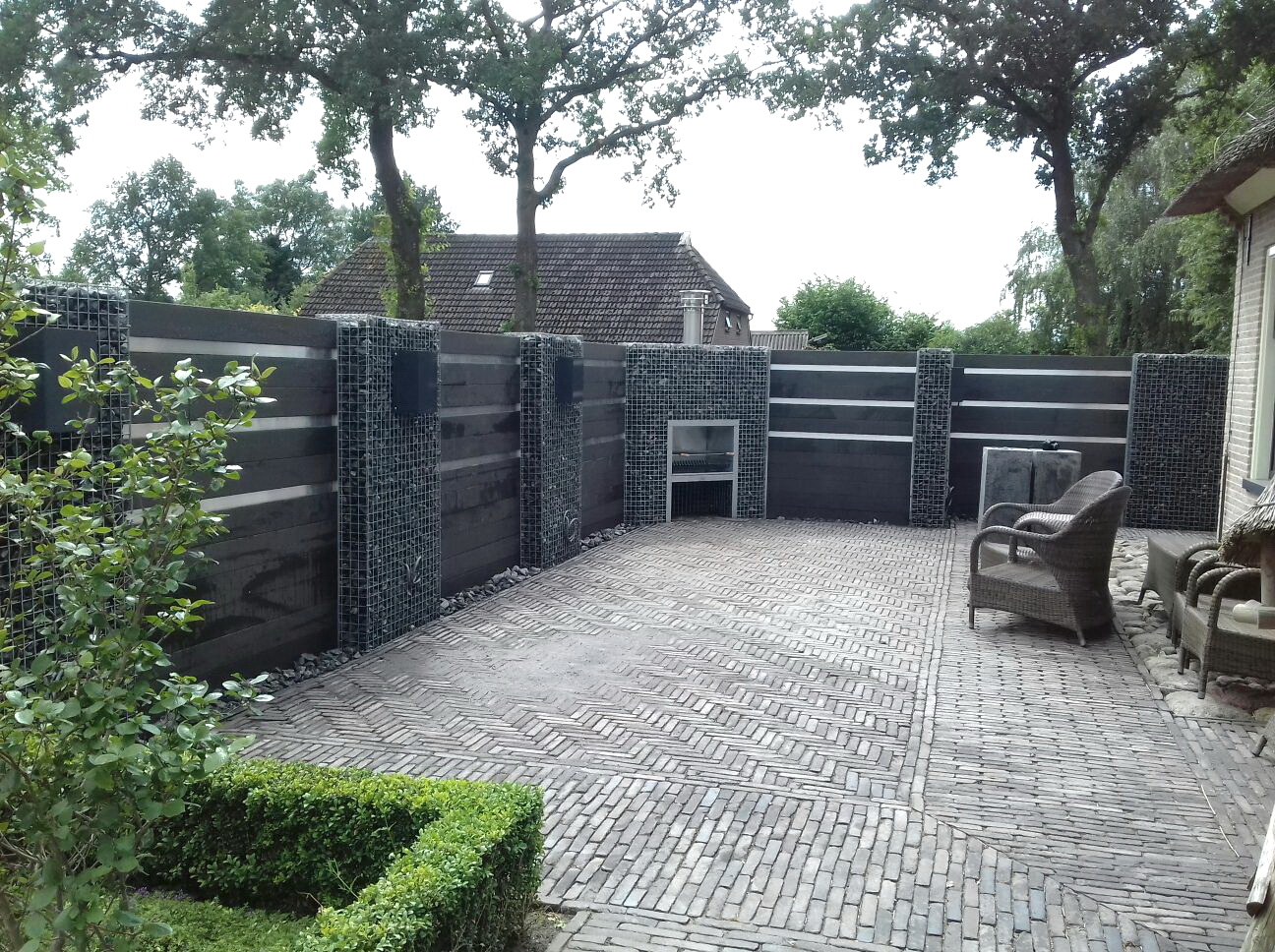 Composiet schutting met schanskorven en openhaard